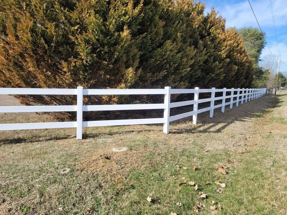 White vinyl three rail farm and paddock fence along a rural roadside