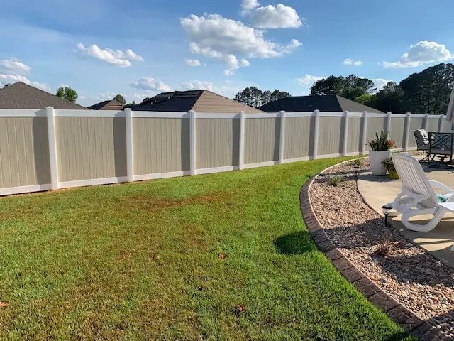 Two tone tan and white vinyl privacy fence along a curved patio edge