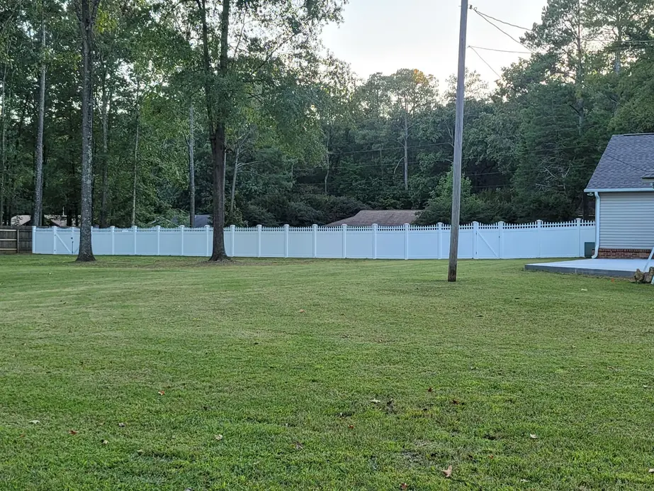 White decorative picket top vinyl fence in a large wooded back yard